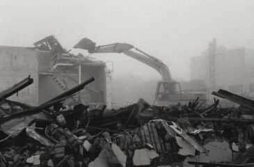 Rubble of a collapsed building, with excavator in the background, in downtown Santa Cruz